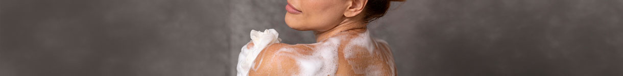 Woman using calming body wash with lather in the shower for a relaxing skin care routine