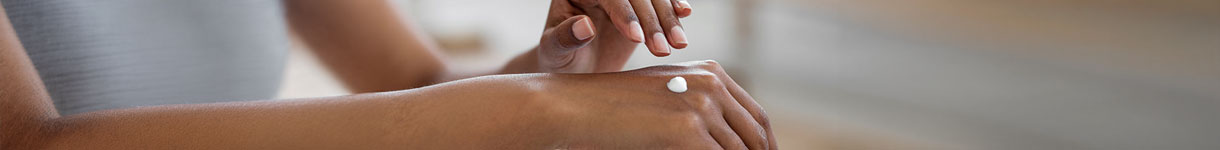 Woman applying rich body lotion to hand to test if moisturizer is hydrating enough for very dry skin