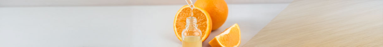 Hyaluronic acid serum dropper with orange fruit showing vitamin C skincare ingredients