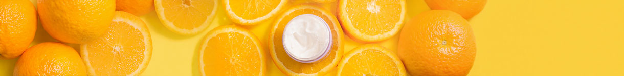 Vitamin C cream jar surrounded by fresh orange slices showing skincare ingredients for brightening and hydration