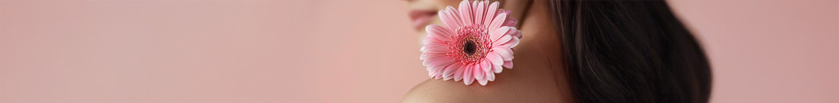 Close-up of a pink flower resting on a shoulder, symbolizing soft, feminine fragrance vibes.