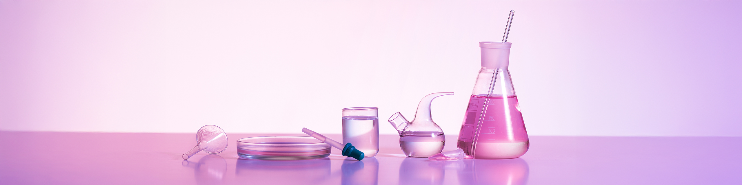 Vegan and cruelty-free skincare ingredients displayed in clear lab glassware with a pink gradient background