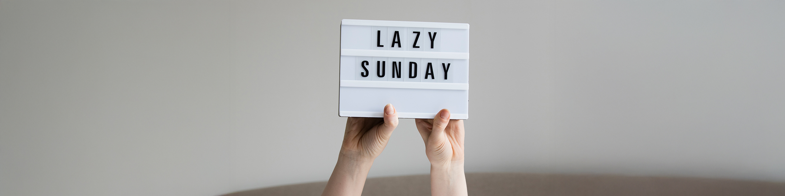 Lightbox sign reading ‘Lazy Sunday’ held up by hands, representing a peaceful and mindful Sunday routine