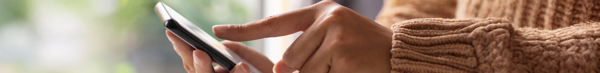 Person using a smartphone while wearing a cozy sweater, illustrating constant digital engagement and screen overload.