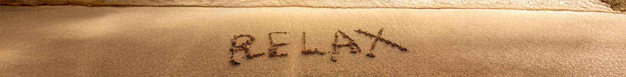 beach sand with the word ‘RELAX’ written on the sand, promoting calm and mindful self-care breaks.