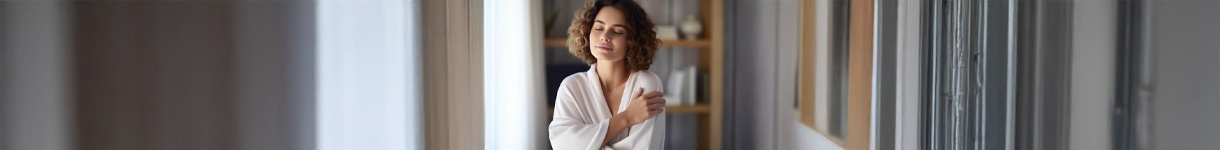 Woman smiling with her hand over her heart, symbolizing self-love and emotional well-being.