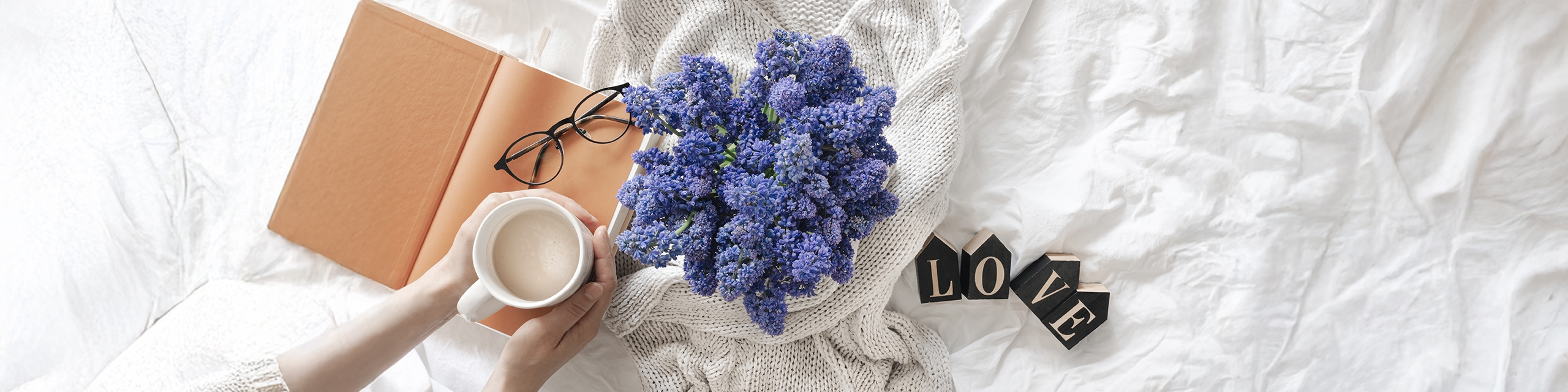 Top view of lavender flowers, a warm drink, and an open journal on a soft bed, symbolizing soothing lavender self-care moments.