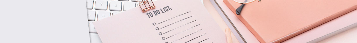 Open planner with a resolutions checklist next to a keyboard and a pink pen, symbolizing New Year goal-setting