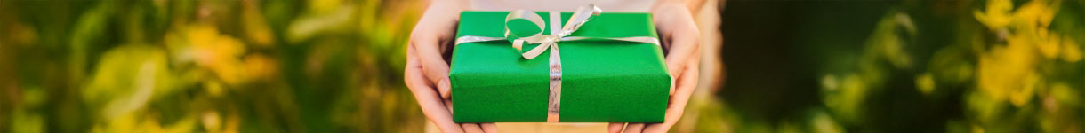 Close-up of hands offering a green gift box, representing ethical gifting and vegan beauty choices