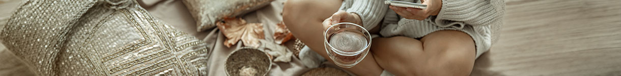 Hands holding warm cup while scrolling on phone representing the need to slow down and disconnect for intentional living